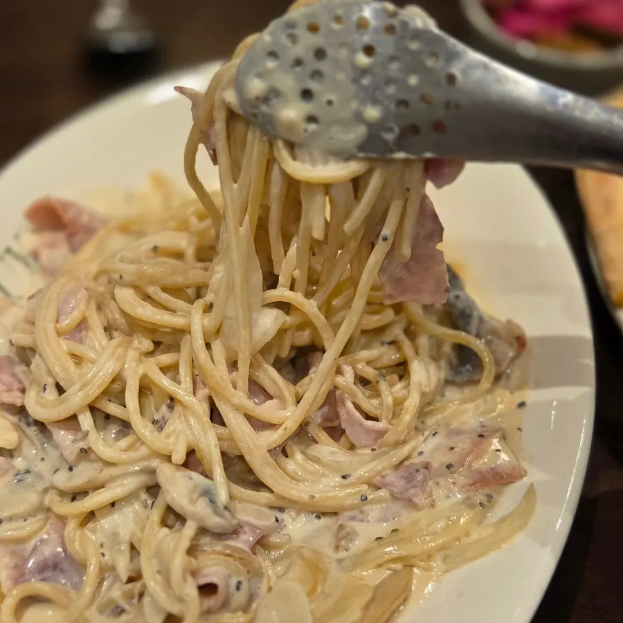 Thick carbonara noodles twirled around a fork