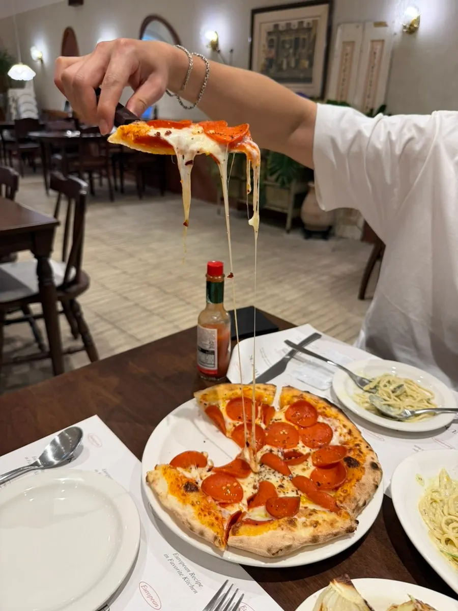 A slice of pepperoni pizza with cheese stretching long