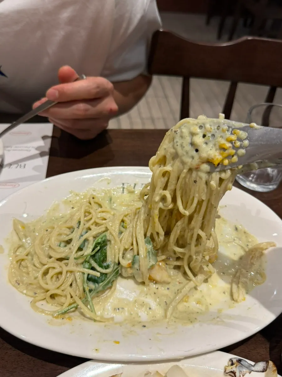 A forkful of basil pesto cream pasta lifted up