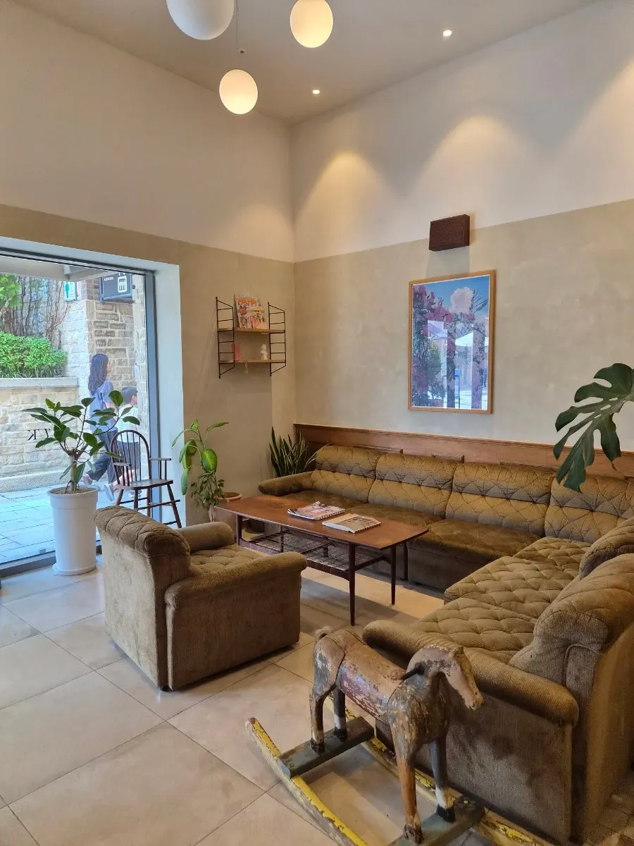 Waiting area by the entrance with a sofa, rocking horse, and wall art