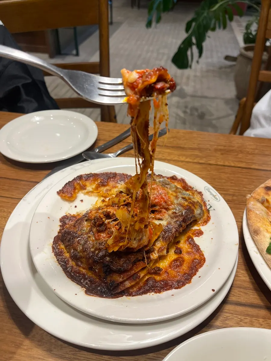 Cross-section of lasagna scooped up with ragu sauce and cheese