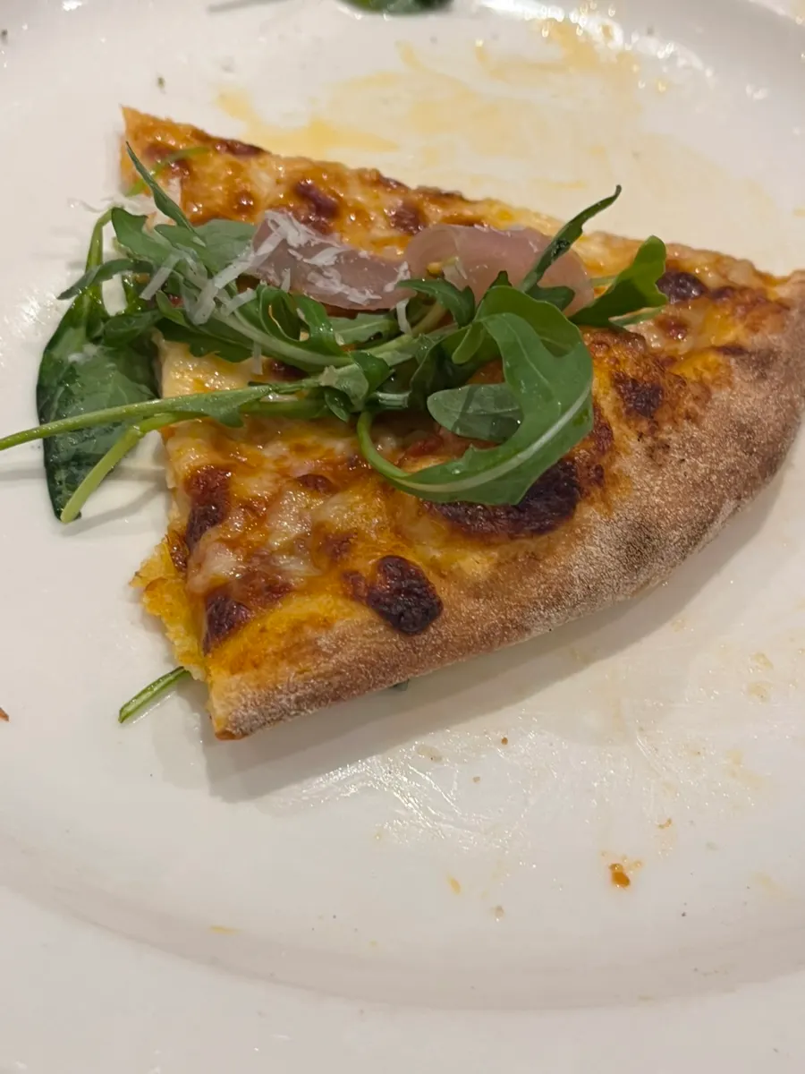 A slice of pastry-dough arugula pizza