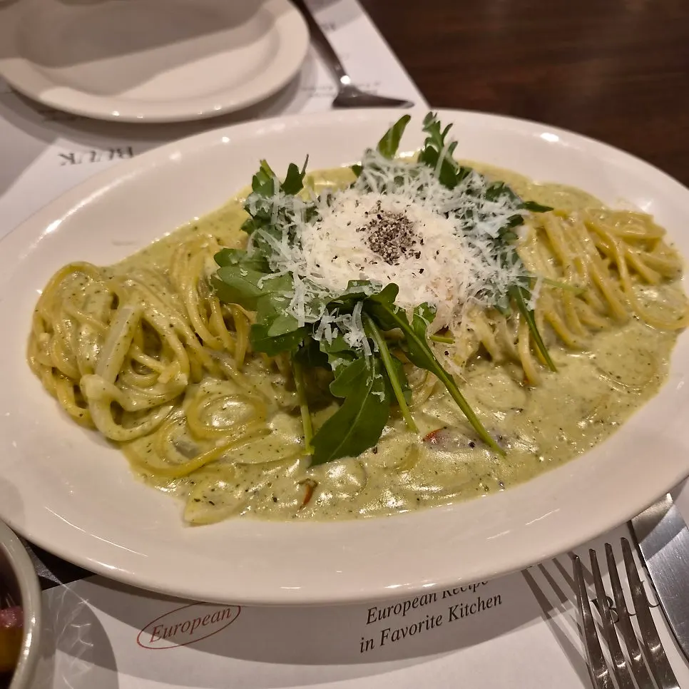 Basil pesto cream pasta topped with a poached egg