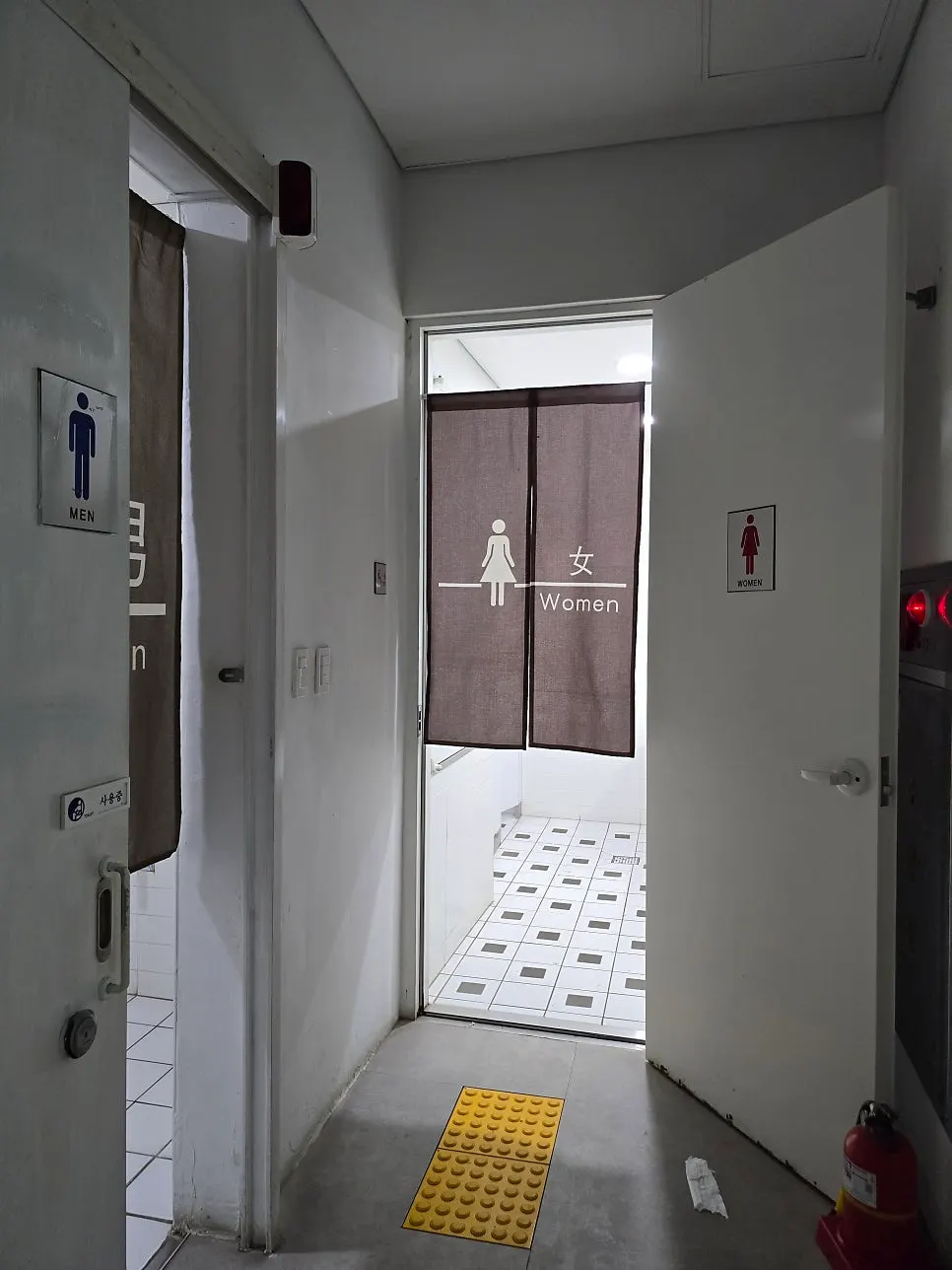 Passage with restroom signage beside the parking lot