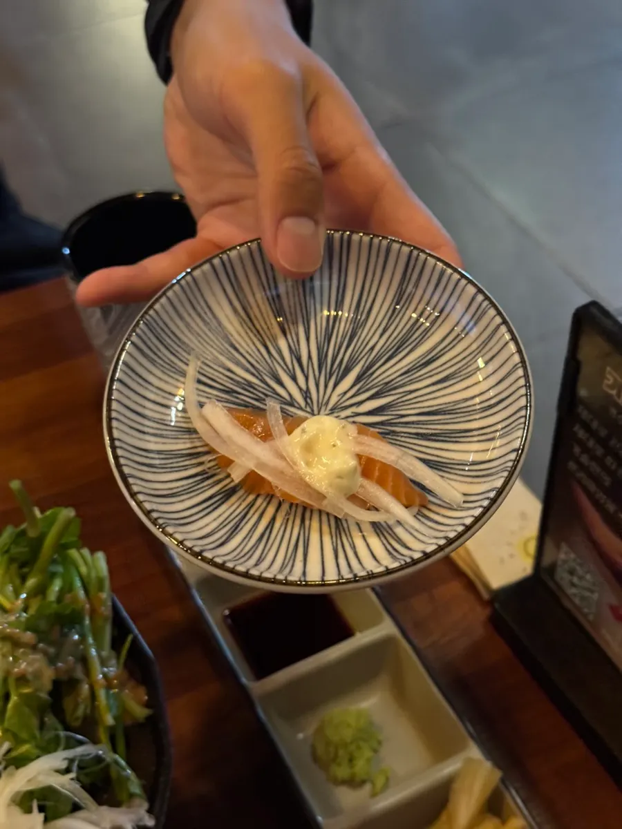 A piece of salmon sashimi topped with poached-egg sauce