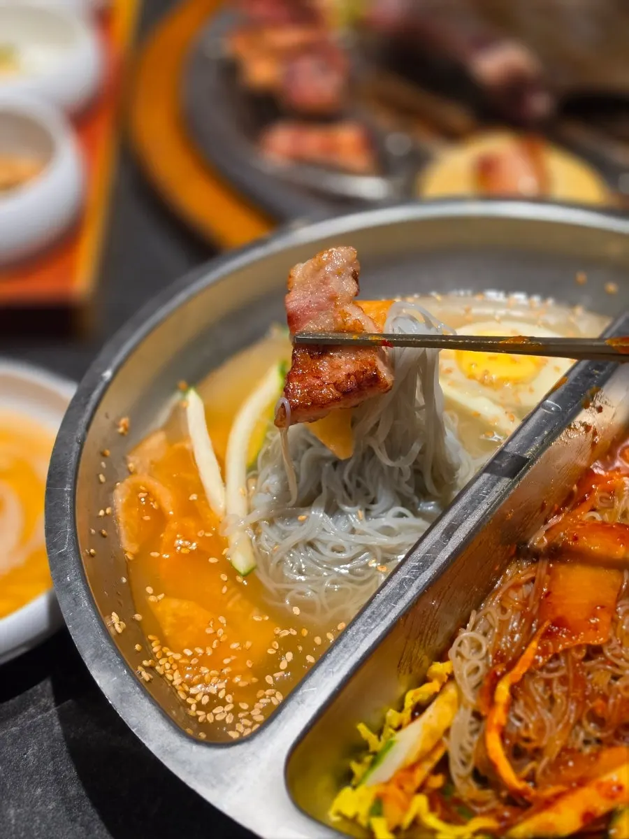 A bite of naengmyeon noodles with a piece of meat