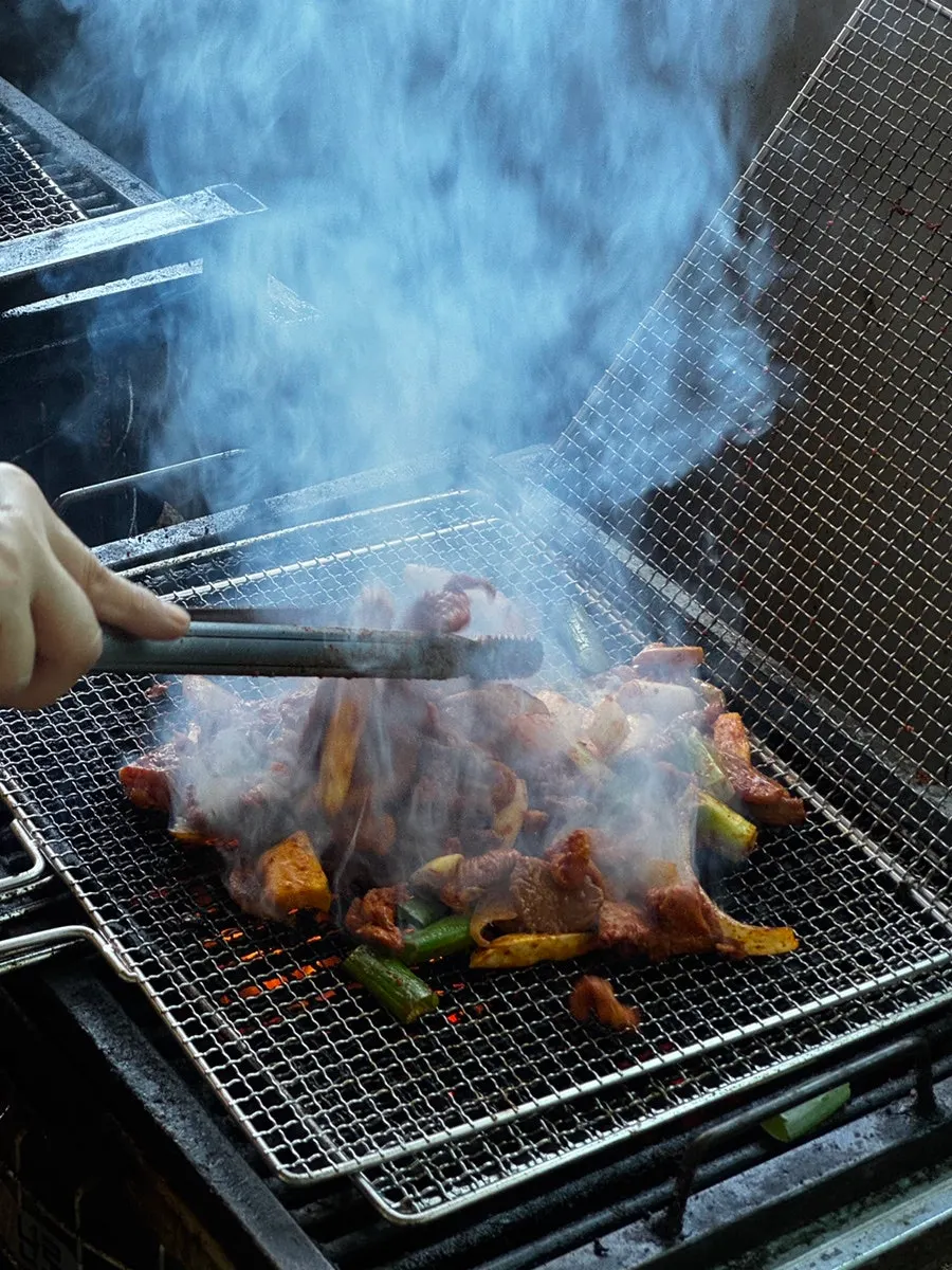 Flames rising during the charcoal pre-grilling of duck jumulleok