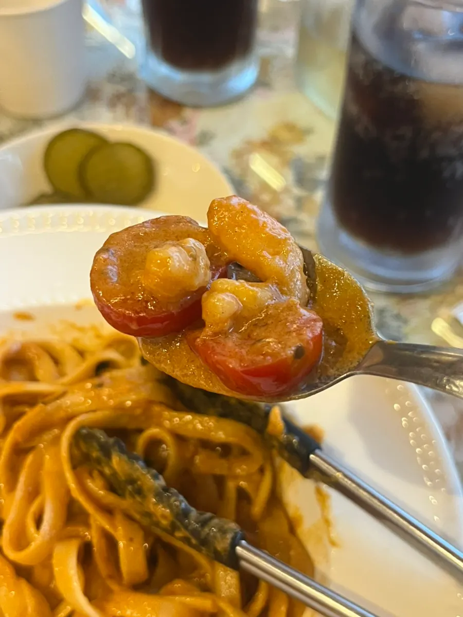 Red shrimp bisque pasta noodles and sauce mixed with tongs