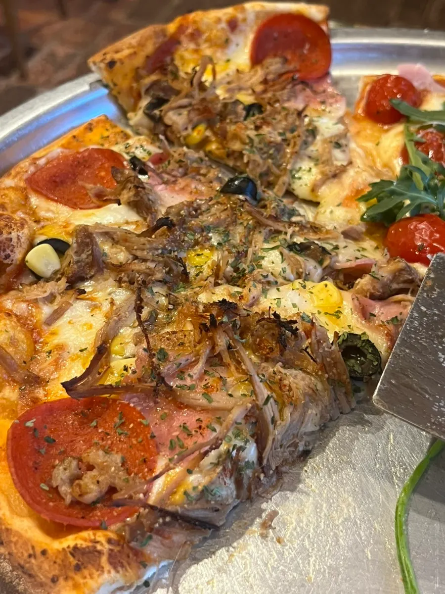 A slice of the Jeongmiso combination pizza topped with pulled pork