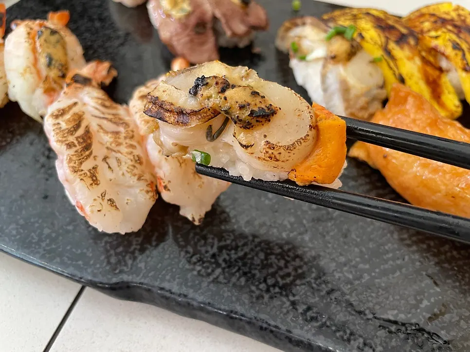 Picking up a piece of flame-seared sushi