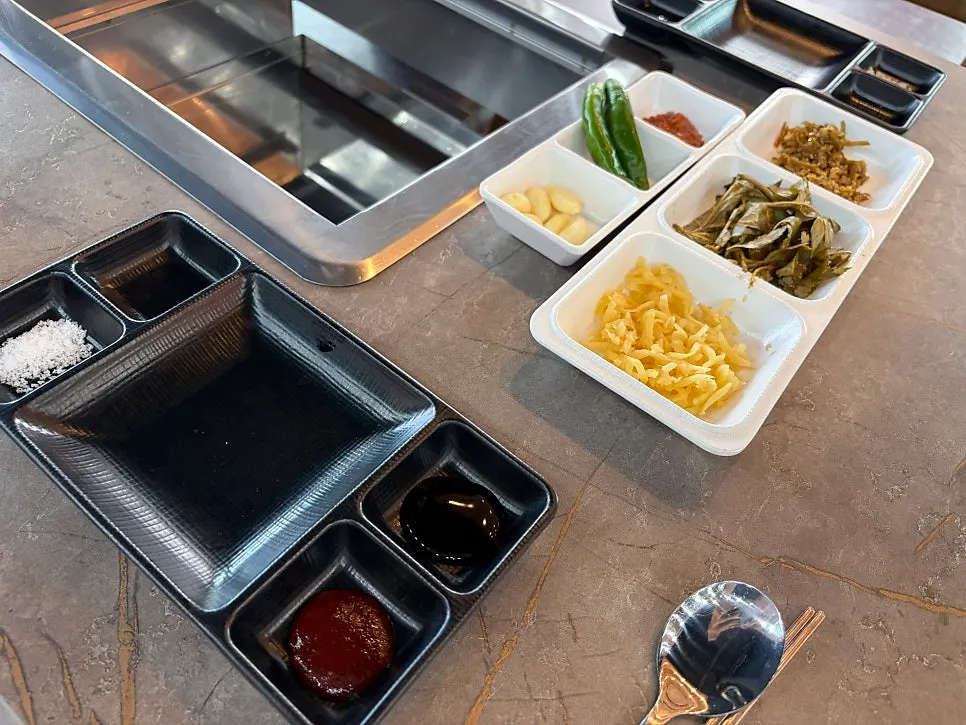 Side dishes including small plates, ginger strips, and pickled perilla leaves