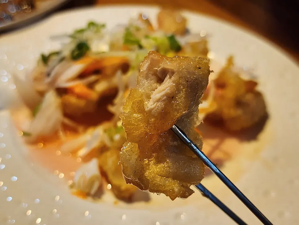 A piece of tangsuyuk with onion and carrot on top