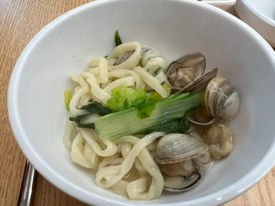 A spoonful of kalguksu topped with clam meat