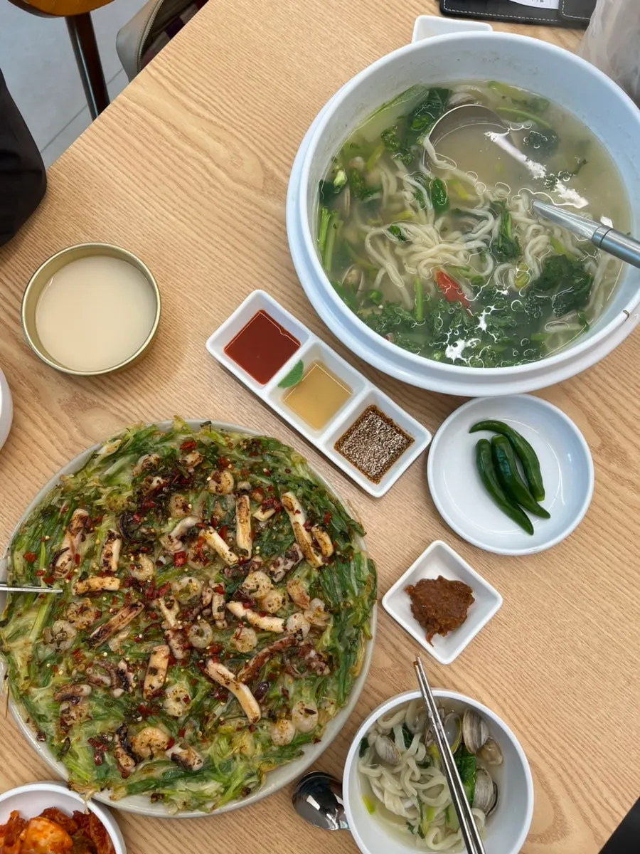 Table spread of kalguksu, seafood pancake, and kimchi