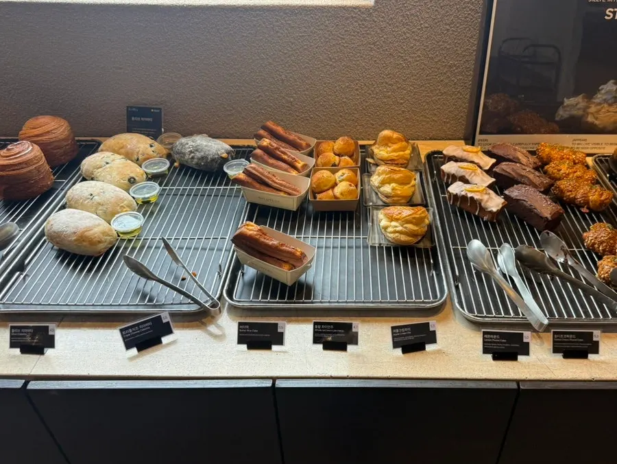 Bakery menu board listing tomato focaccia, lemon meringue croissant, and more