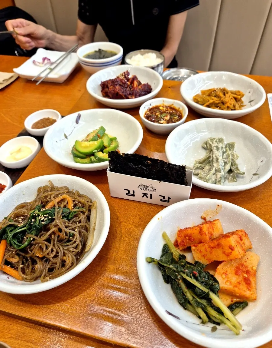Side dish spread of japchae, namul, and kimchi-jjim at Gaya Kkeutjip