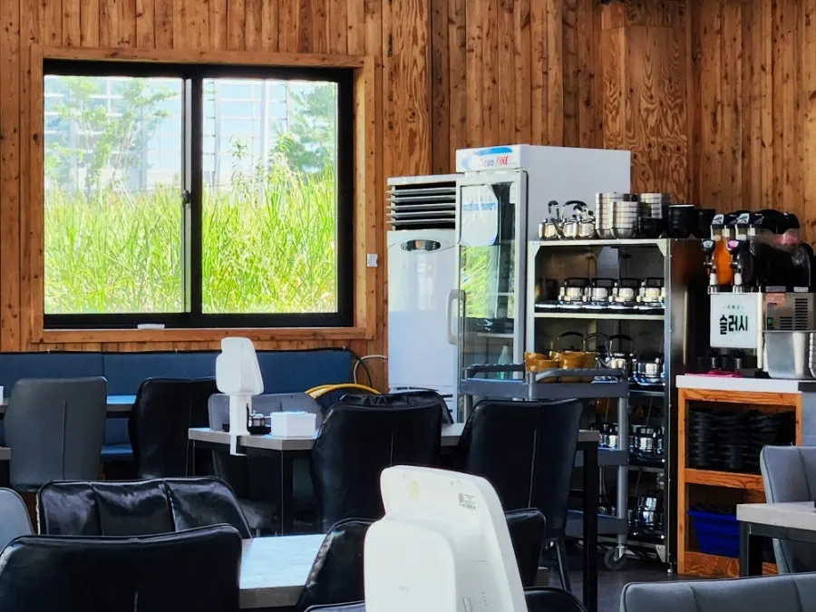 Wood-toned restaurant interior with green scenery outside the window