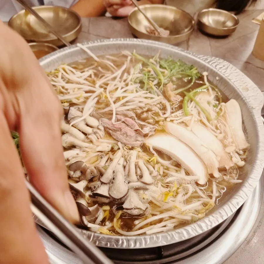 在滾湯中煮熟的水芹與菇類