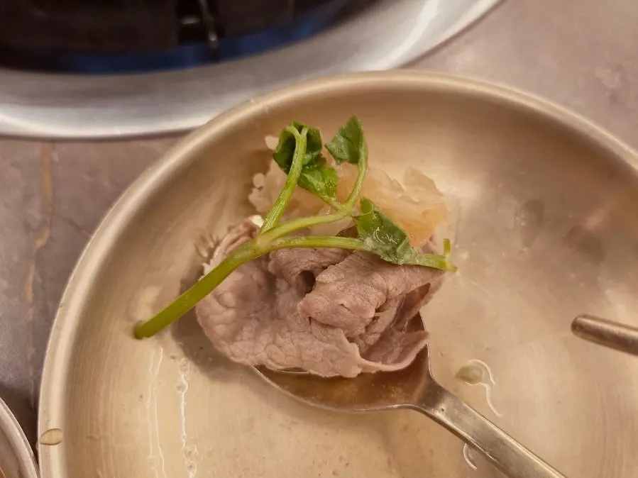 肉片與水芹一起夾起食用的畫面