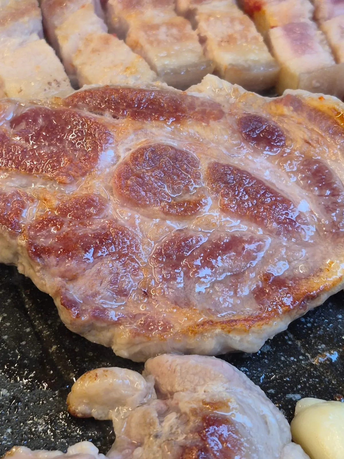 Pork belly grilling to a golden brown on the hot pan