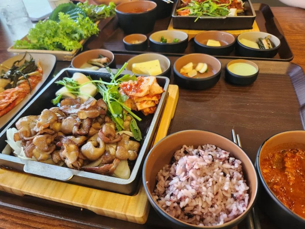 Full lunch table set with charcoal-fired meat and kimchi jjigae
