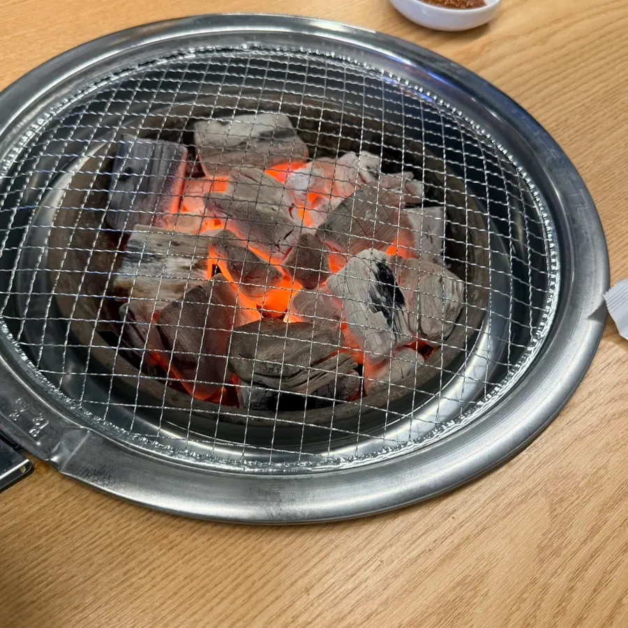 Glowing red charcoal placed under the grill