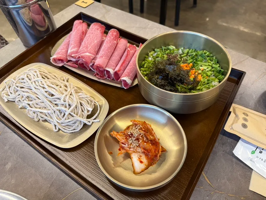 Pot of agaricus mushroom shabu-shabu with bok choy, sprouts, and mushrooms
