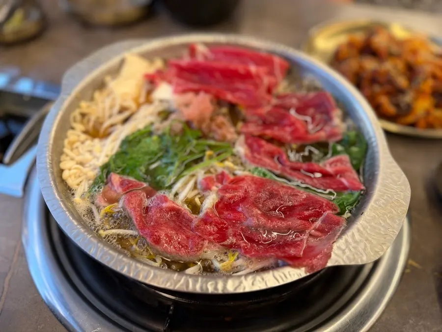A slice of boiled pork topped with bossam radish kimchi and garlic