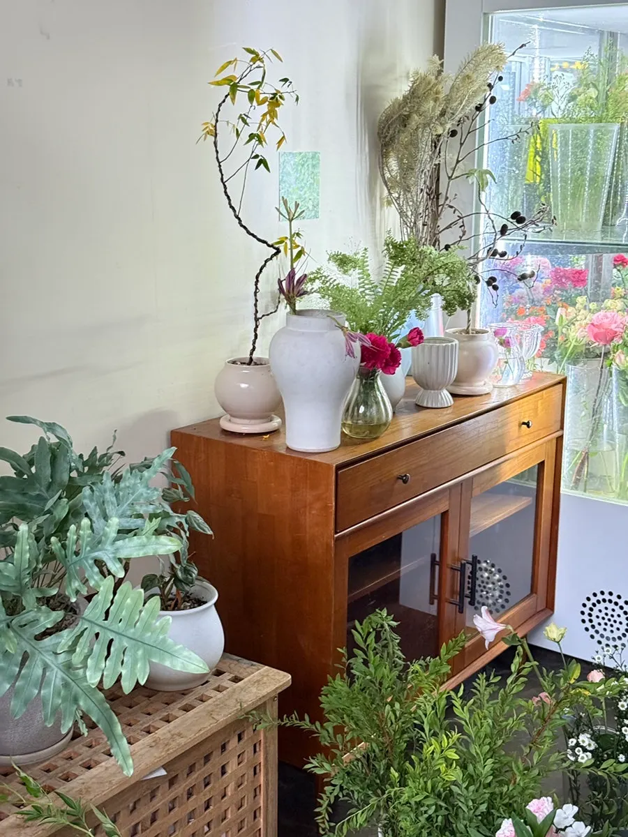 Round wooden table and potted plants on a three-tier wood shelf