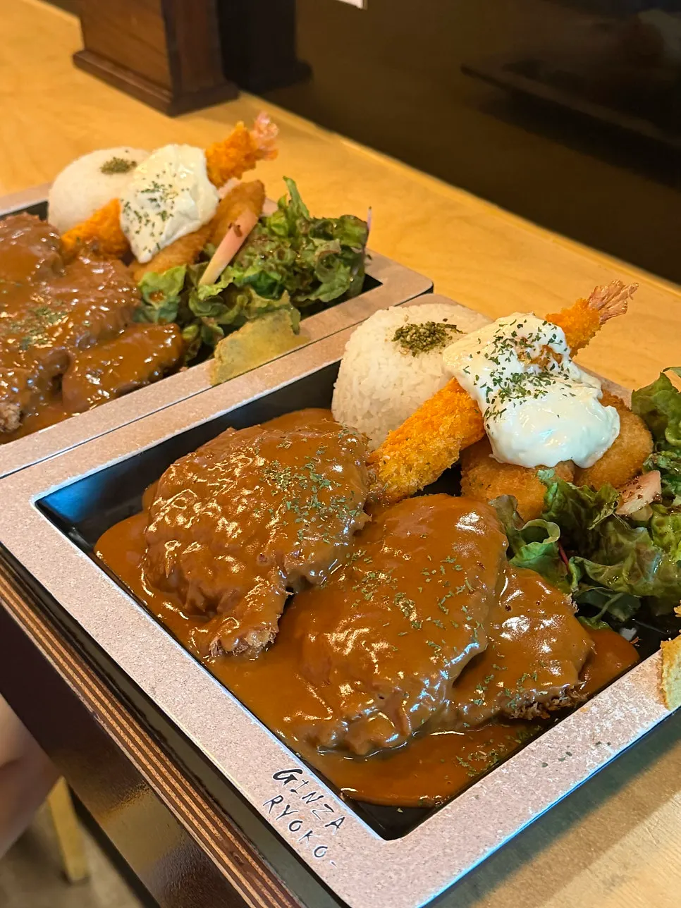 Plate packed with two cutlets, tempura, rice, and salad