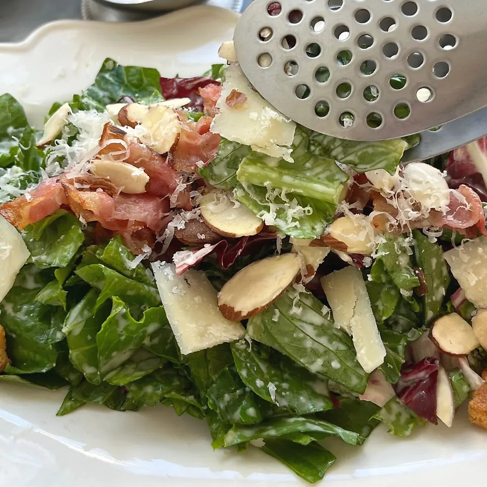 Close-up of Caesar salad topped with bacon and cheese