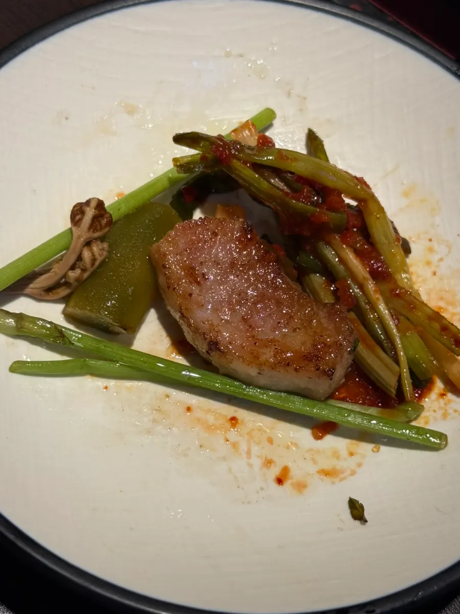 A bite combining grilled vegetables and minari on top of the meat