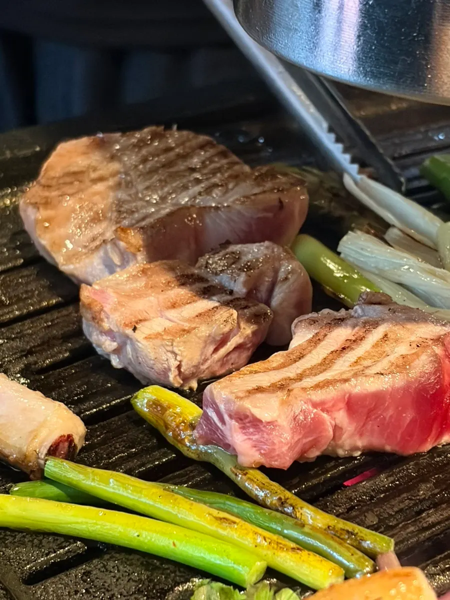 Baek-kimchi grilling on the pan alongside the meat