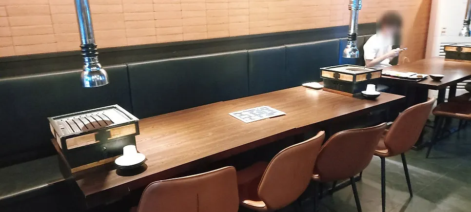 Tempat duduk berbentuk booth dengan meja kayu dan sofa gelap