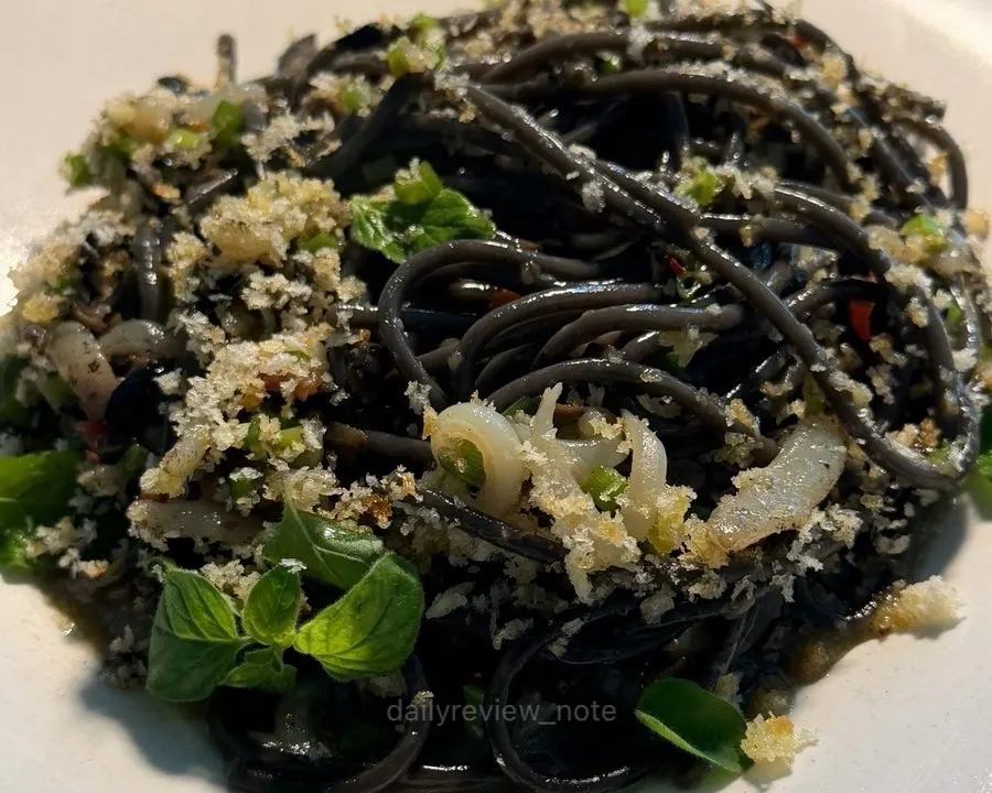 Pasta plate topped with cuttlefish and herbs