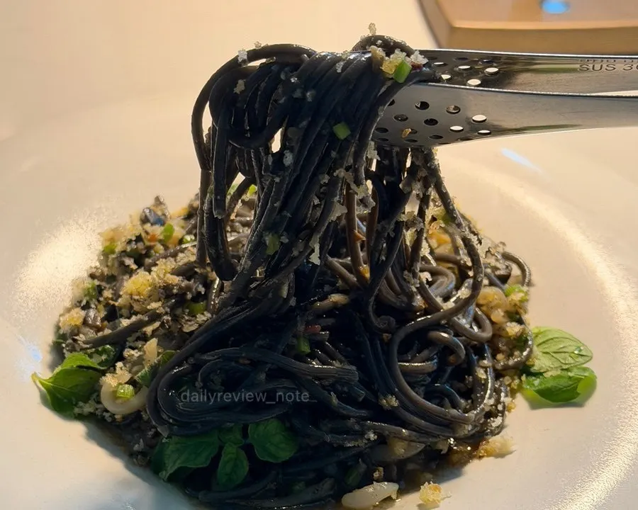 Cuttlefish pasta plated with crunchy crumble on top