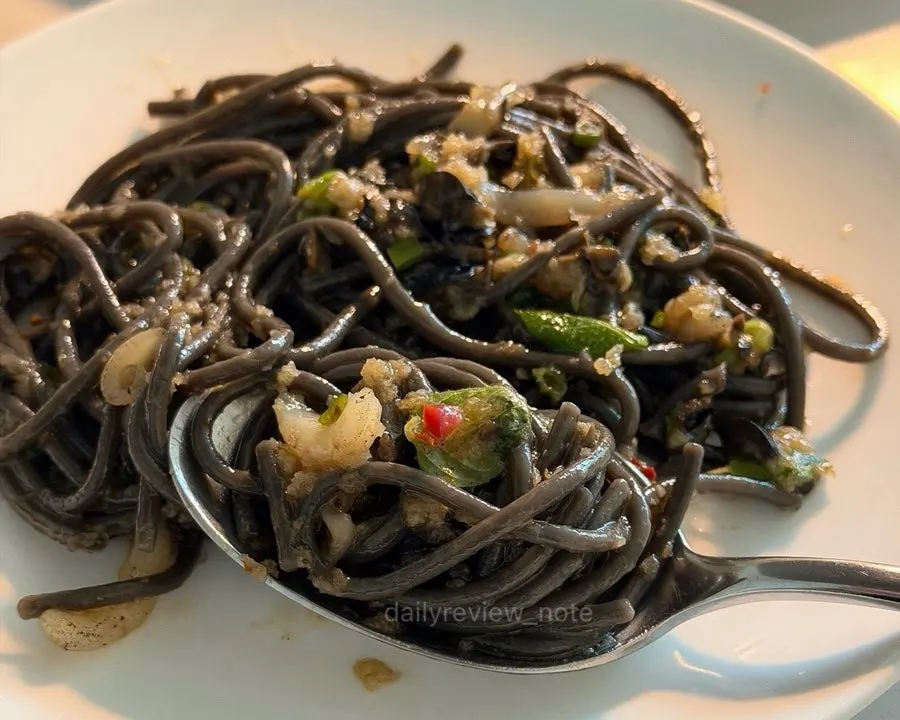 Forkful of cuttlefish pasta noodles being lifted