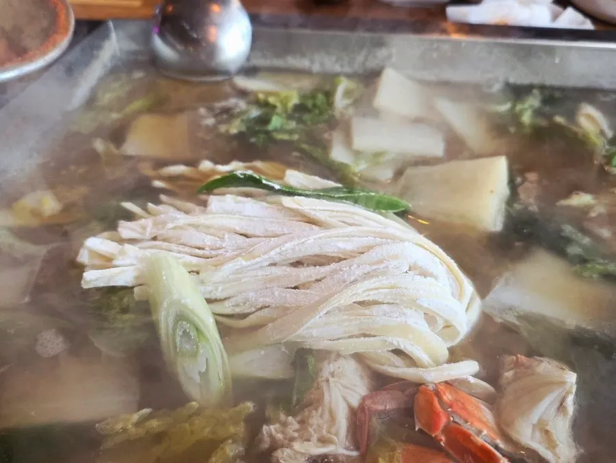 Kalguksu noodles added to the steamed clam broth