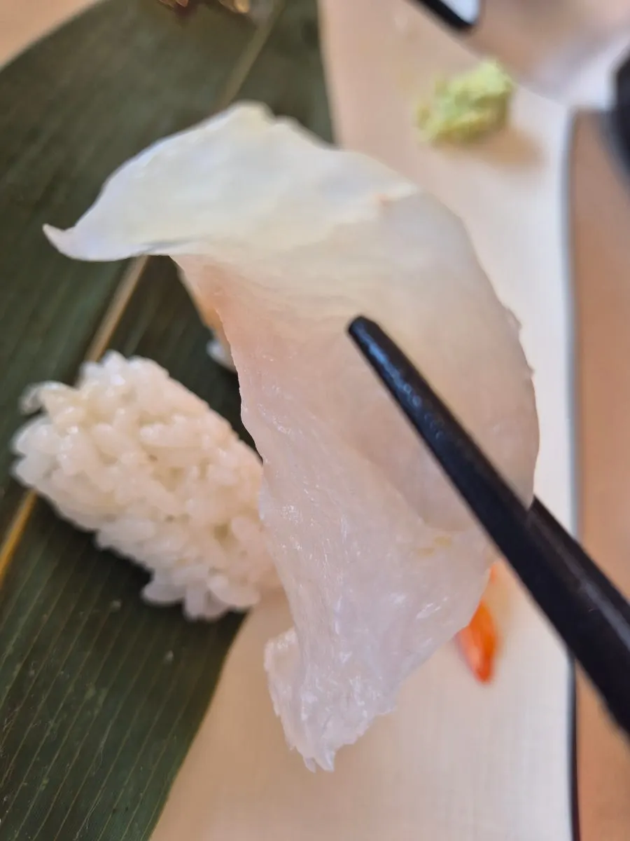 A piece of aged sashimi sushi served with light broth