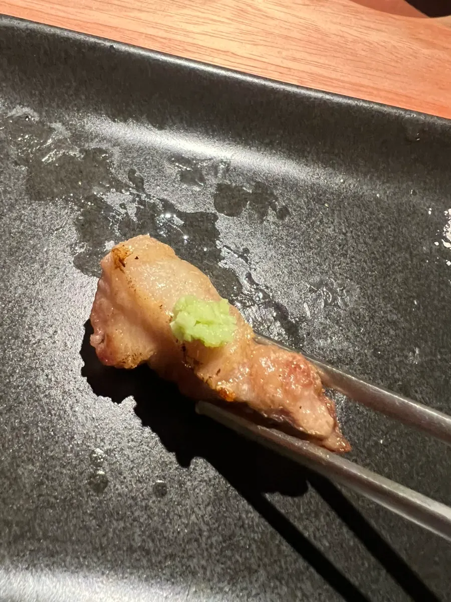 A piece of samgyeopsal topped with fresh wasabi