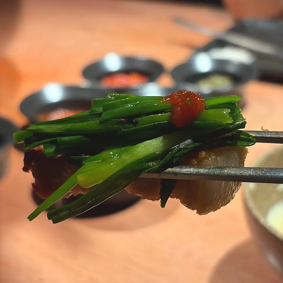 Green onions grilling alongside the pork belly