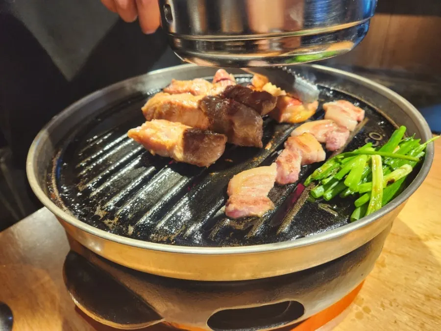 Meat being grilled on the cast-iron grill during the grilling service