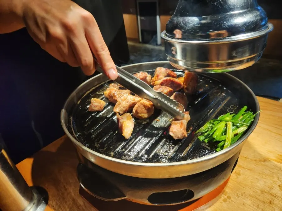 A thick cut of pork neck being grilled