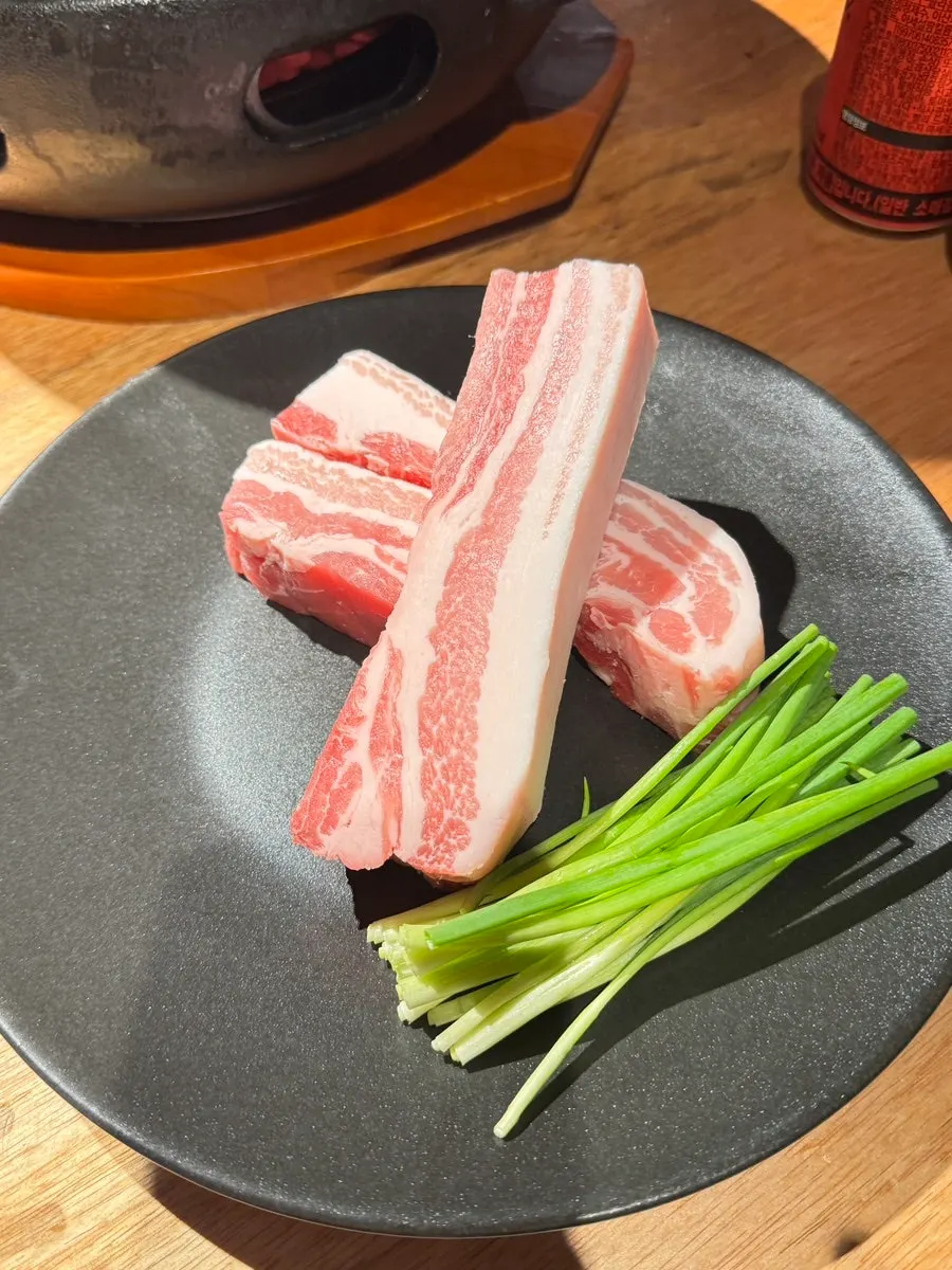 Plate of white kimchi, mustard leaf kimchi and other side dishes