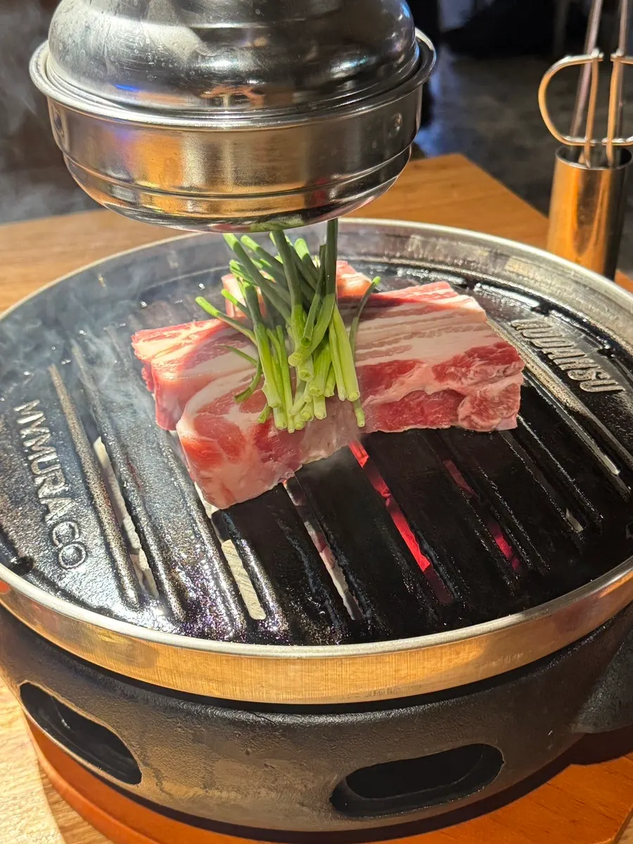 Pork belly grilling over the charcoal brazier