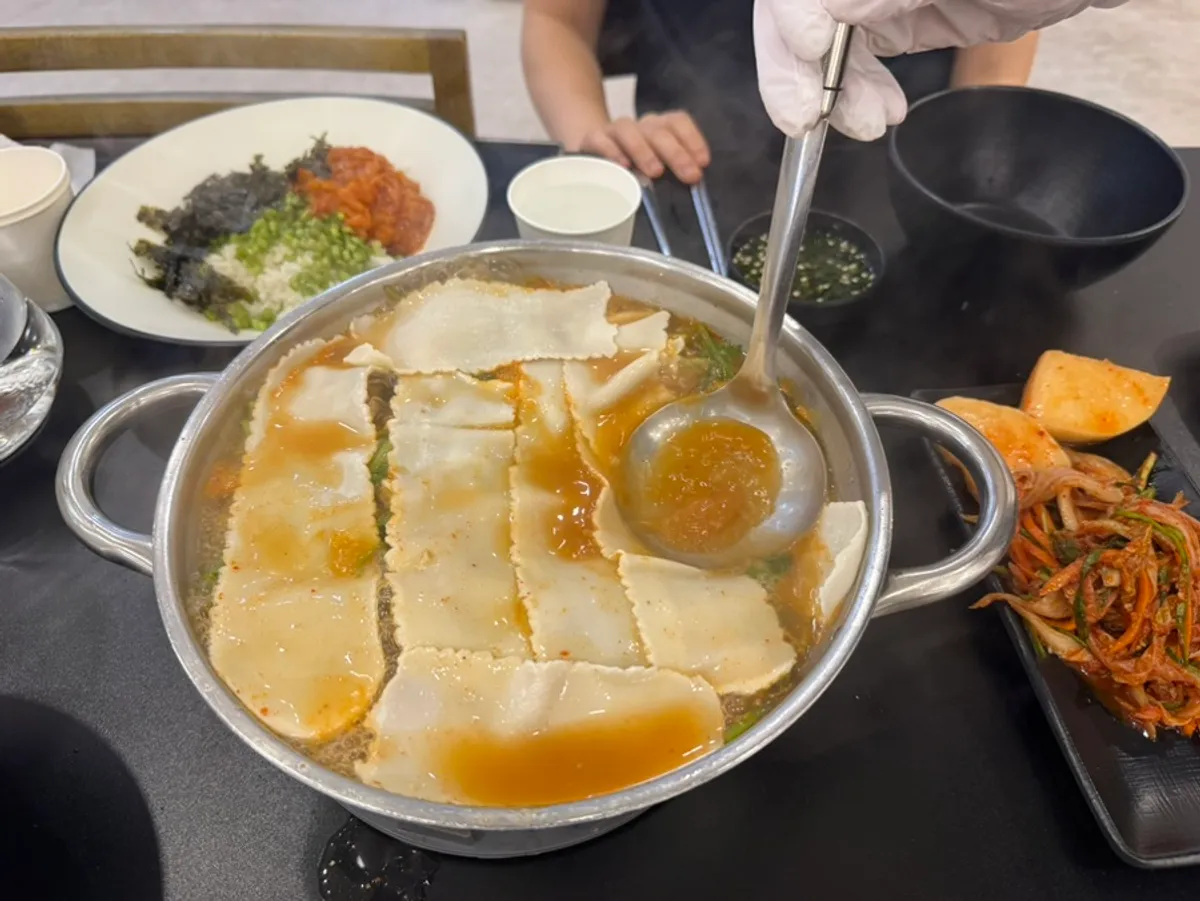Kalguksu noodles cooking in the red broth