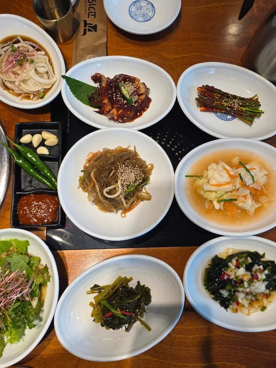 A plate of japchae, seasoned vegetables, and kimchi side dishes