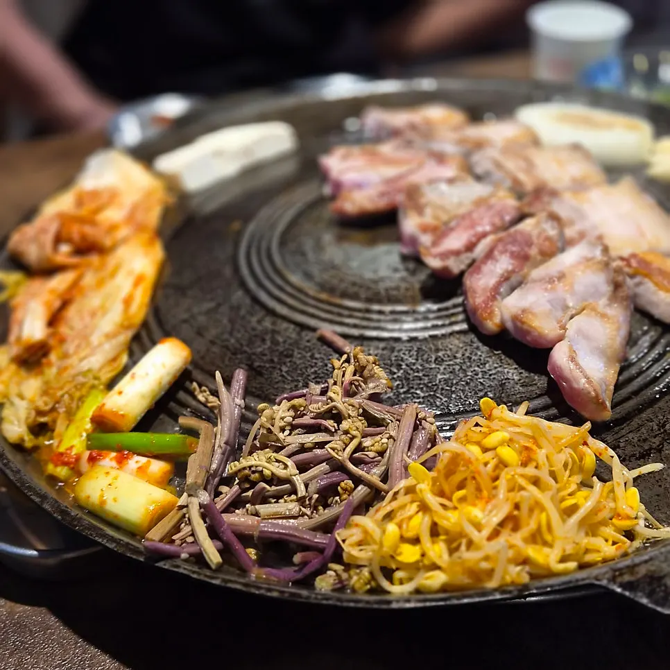 고기와 함께 솥뚜껑에 구워지는 양파와 콩나물