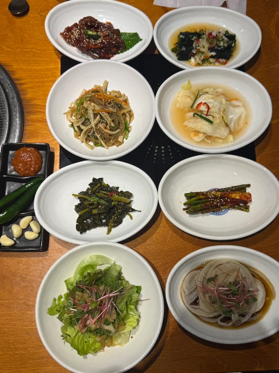 Table setting with 8 basic side dishes including marinated crab and japchae