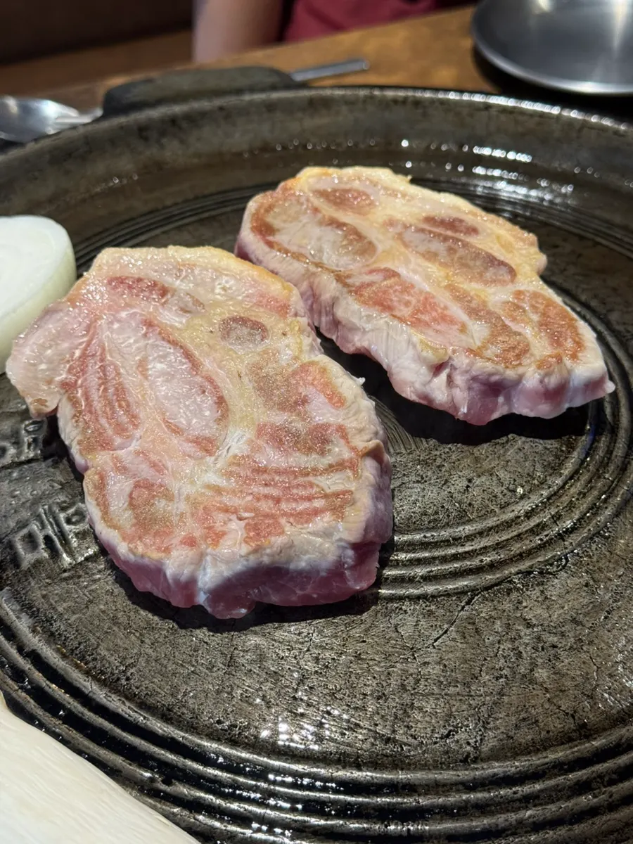 Thick pork neck cooking on the cauldron lid